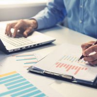 businessman analyzing annual business report with using laptop at office desk